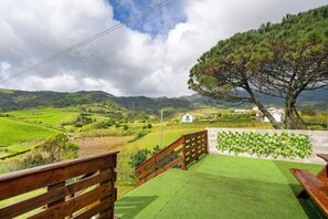 A view of a green landscape with a wooden fence, a bench, and a tree.