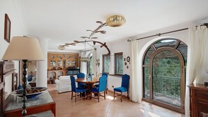 Un comedor con una mesa, sillas, una araña y vistas por un gran ventanal.