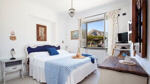 Un dormitorio con cama, mesitas de noche, escritorio, televisor y ventana con vistas.