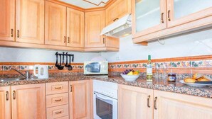 A kitchen with wooden cabinets, a microwave, a stove, and a tiled backsplash. - 2 Bedroom, 2 Bathroom Villa in Great Location (Playa Blanca)