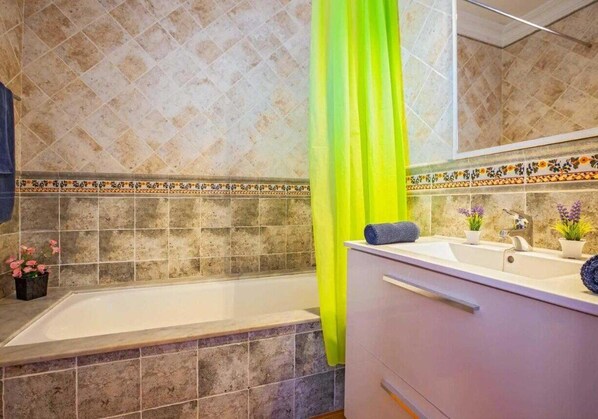 Een badkamer met een bad, een wastafel en een spiegel.