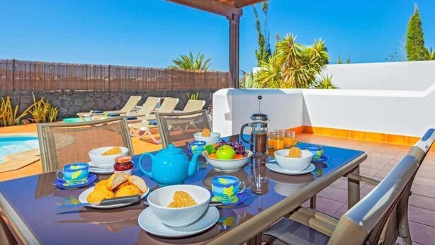 An outdoor breakfast setup with a table, chairs, and a view of the pool and landscape. - 2 Bedroom, 2 Bathroom Villa in Great Location (Playa Blanca)