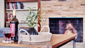 Una mesa de madera con una botella de vino, una copa, una cesta tejida y una planta en maceta.