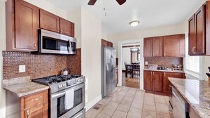 Una cocina moderna con gabinetes de madera, electrodomésticos de acero inoxidable y salpicadero de azulejos.