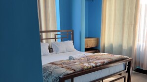 A bedroom with a wooden bed, blue walls, and a ceiling fan. - Kilimanjaro Smiley Inn (Moshi)