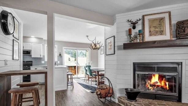 Una cocina moderna con armarios blancos, un comedor con candelabro y una chimenea encendida.