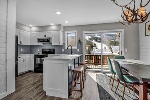Une cuisine moderne avec des meubles blancs, un îlot central et un coin repas comprenant une table et des chaises.