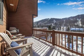 Un balcon en bois offrant une vue sur des montagnes enneigées et un ciel dégagé.