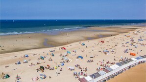 A beach with numerous sunbeds and umbrellas, a sandy shore, and the ocean in the background. - Cozy apartment in Oostende with WiFi (Oostende)