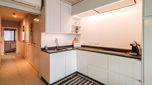 A modern kitchen with white cabinetry, a black countertop, and a built-in oven. - Cozy apartment in Oostende with WiFi (Oostende)