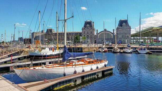 A marina with boats docked, a bridge, and a historic building in the background. - Cozy apartment in Oostende with WiFi (Oostende)
