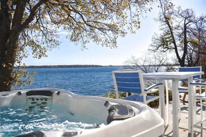 A hot tub with a view of a lake, surrounded by chairs and a table. - Moonglade on Lake Carlos (Alexandria)