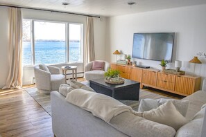A living room with a large window, a flat-screen TV, and a wooden cabinet.