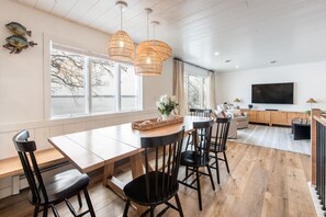 A modern kitchen with a large dining table, black chairs, and a wooden floor.