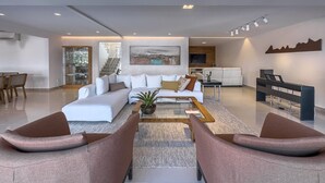 A modern living room with a white sofa, a coffee table, and two brown armchairs.