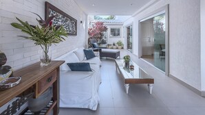 A modern interior with a white brick wall, a sofa, a coffee table, and a potted plant.