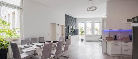 A modern kitchen with white cabinets, a black countertop, and a blue LED light strip.