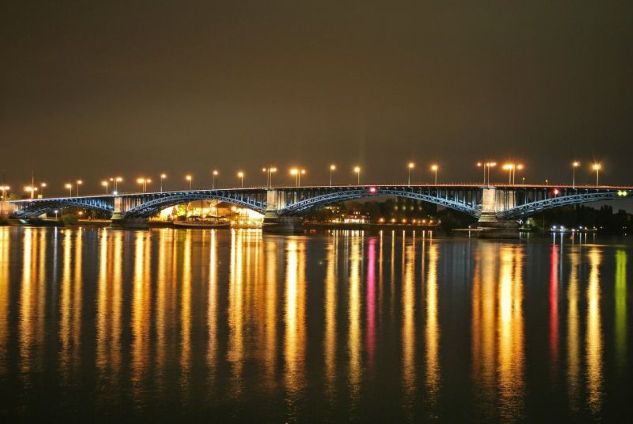 Een nachtzicht van een brug, met lichtreflecties op het water.