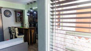 Eine kleine Küche mit Essbereich, einer Wanduhr und einem Fenster mit Jalousien.