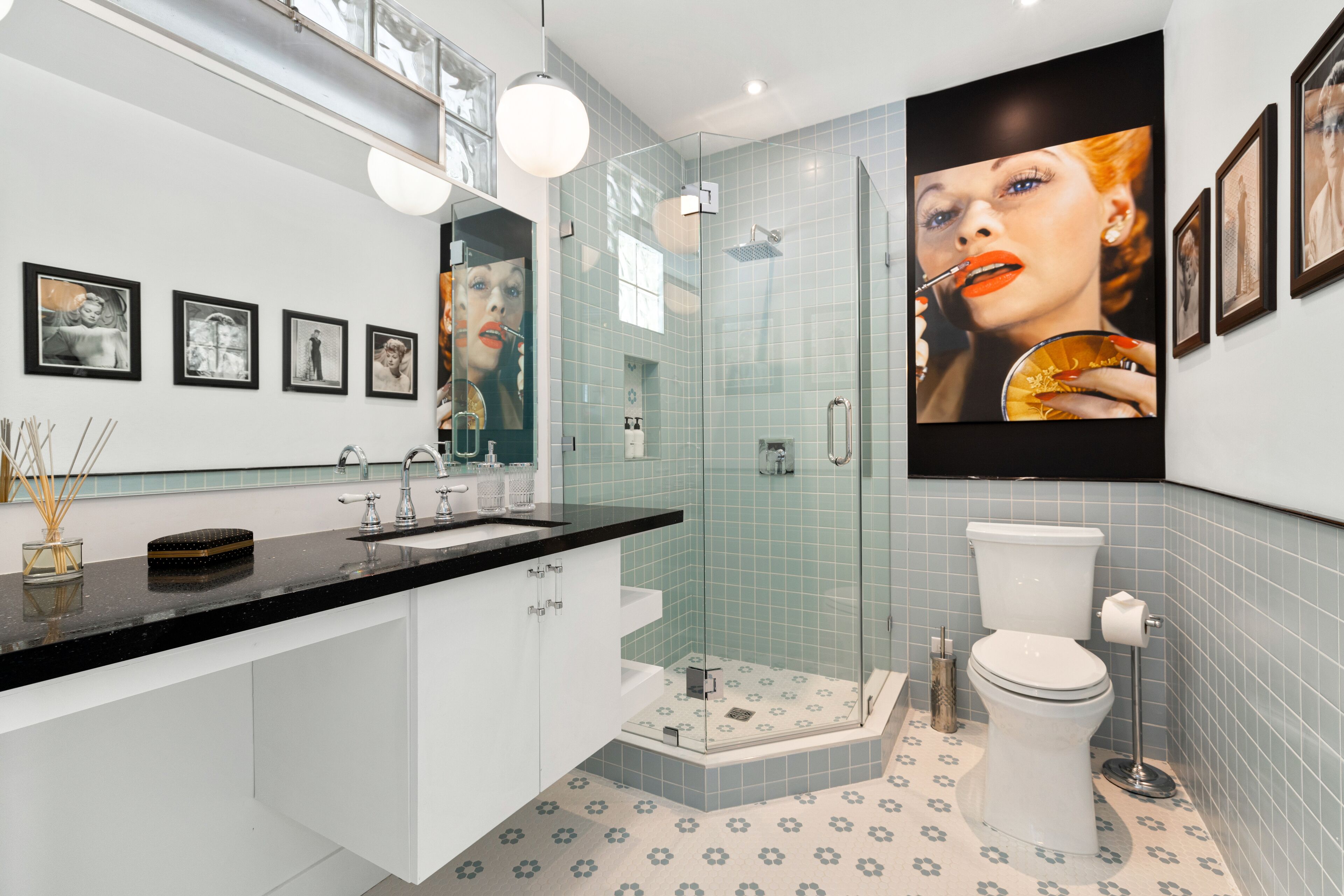 A modern bathroom with a glass-enclosed shower, a large mirror, and a sink with a black countertop.