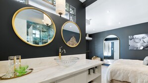 Une salle de bain moderne avec un grand miroir, un lavabo en verre et un meuble-lavabo blanc.