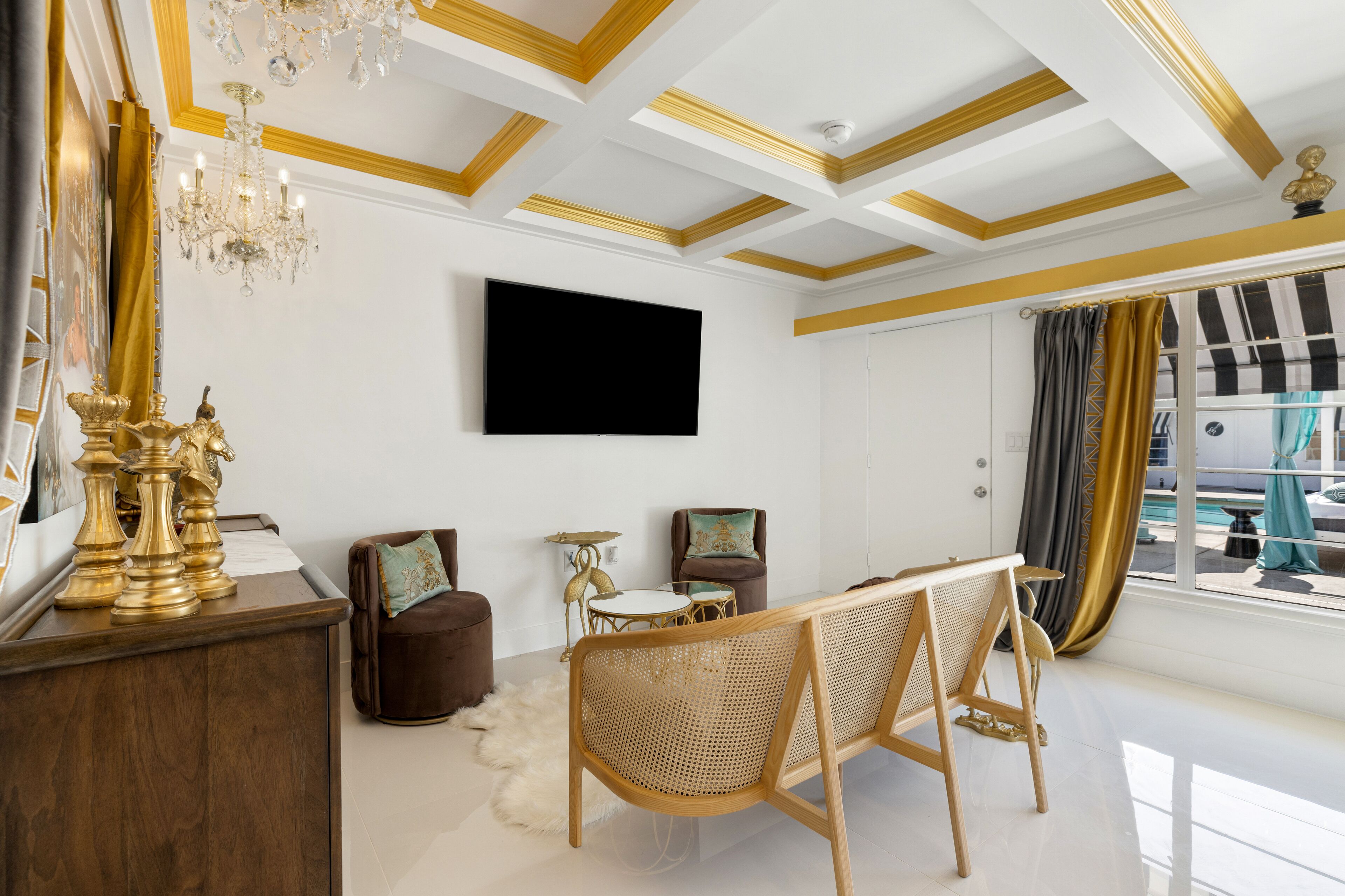 Een moderne woonkamer met een kroonluchter, een flatscreen televisie, een houten salontafel en een bank.