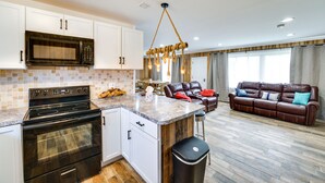 A modern kitchen with a microwave, stove, and bar stools. There is a leather sofa and a dining area in the living room. - Quiet Country Home By Shay Lake! (Silverwood)