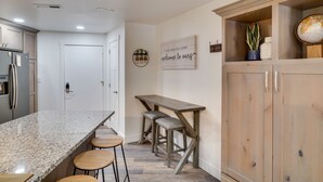 A kitchen with a granite countertop, wooden stools, and a wooden table. - Brian Head Condo w/ Balcony, Grill & Mountain View (Brian Head)