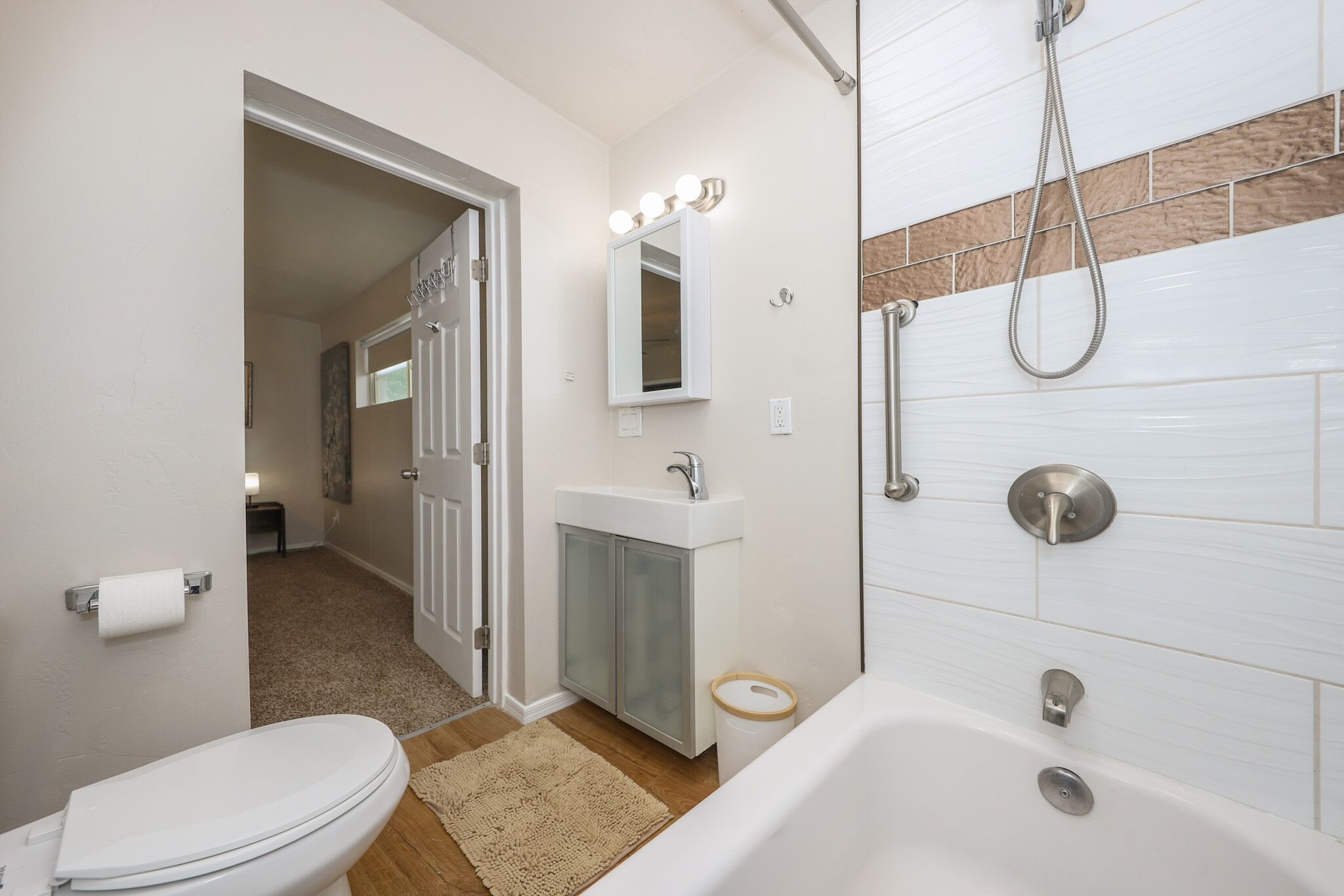A bathroom with a toilet, sink, mirror, and shower.