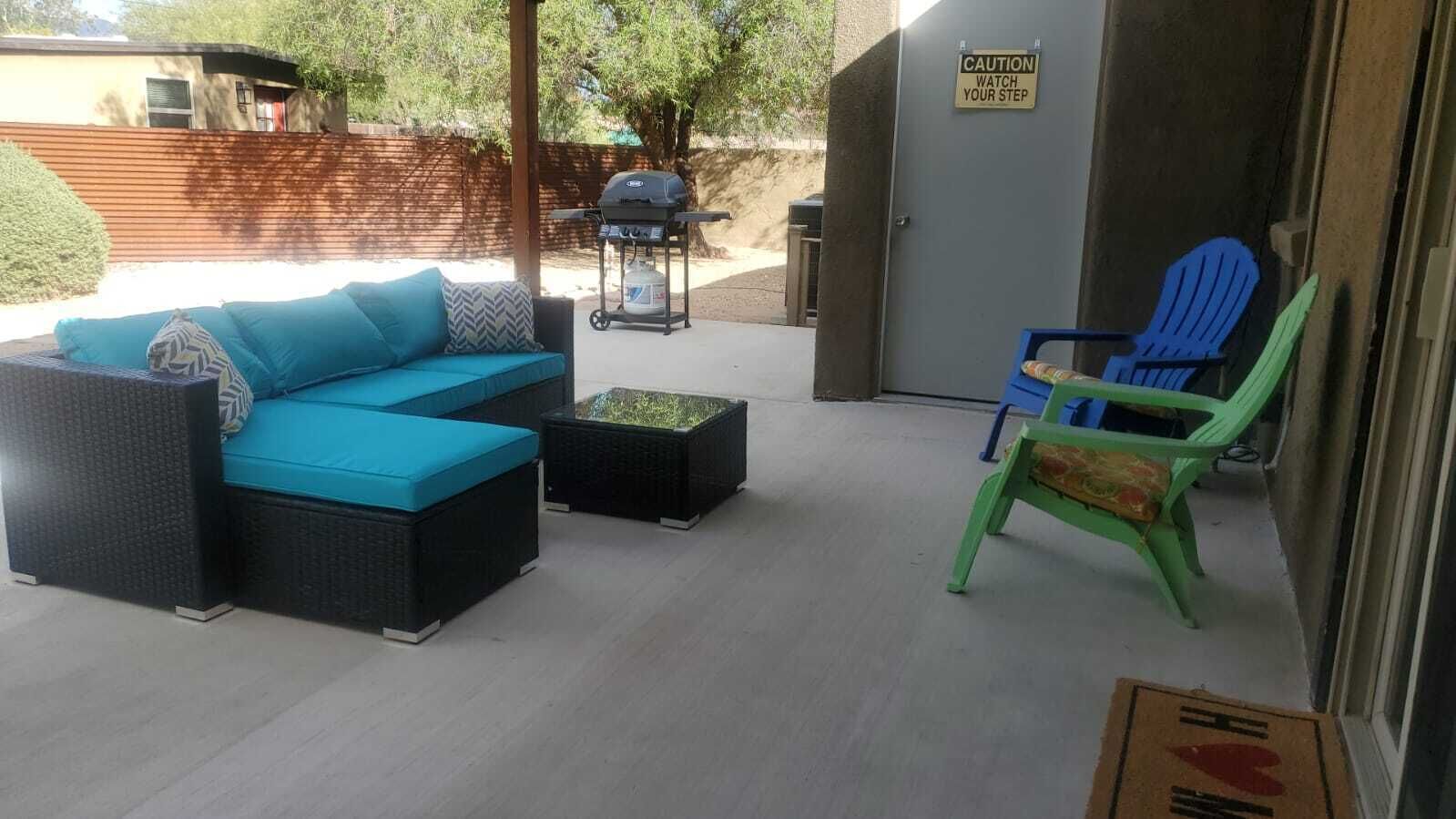 An outdoor patio with a sofa, chairs, and a grill.