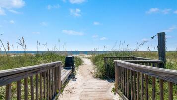 A wooden boardwalk leading to a beach with a wooden structure on the right.