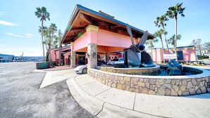Un edificio con fachada rosa, base de piedra y una gran escultura de un ave.