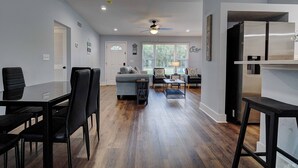 Una sala de estar moderna con comedor, cocina y ventilador de techo.