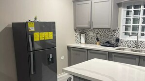 Eine moderne Küche mit einem schwarzen Kühlschrank, einer weißen Arbeitsplatte und grauen Schränken.