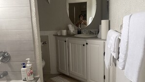 Un baño con bañera, lavamanos, espejo y perchero para toallas.