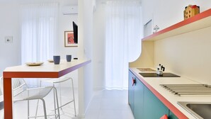 Una cocina moderna con encimera blanca, un lavamanos y un ventanal pequeño.