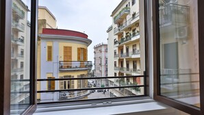 A view from a window of a building with balconies, a curved facade, and a street below. - GuestHost - Casa Maya - Prime Central Apartment (Salerno)