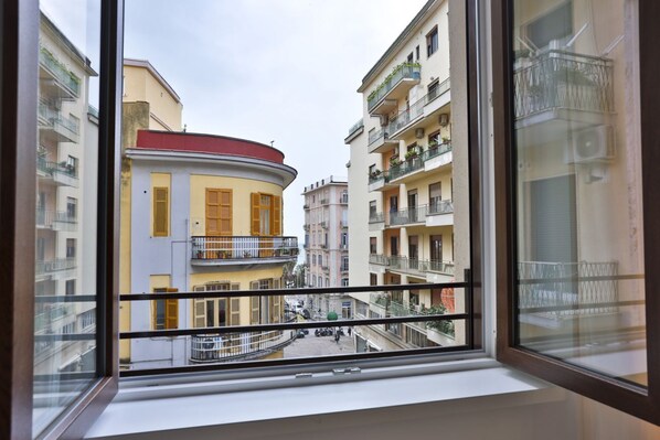 A view from a window of a building with balconies, a curved facade, and a street below.
