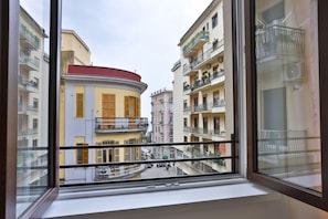 A view from a window of a building with balconies, a curved facade, and a street below.