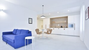 A modern living room with a blue sofa, a white table, and wicker chairs. - GuestHost - Casa Maya - Prime Central Apartment (Salerno)