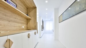 A modern kitchen with wooden shelves, white cabinets, and a long hallway leading to a bright room. - GuestHost - Casa Maya - Prime Central Apartment (Salerno)
