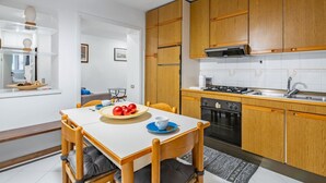 Una cocina moderna con armarios de madera, una mesa de comedor con sillas y una pequeña isla de cocina.