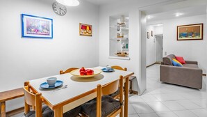 Un comedor con una mesa blanca, sillas y un reloj en la pared.