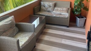 A room with a wicker sofa, a small table, and a potted plant. - Charming 1-bedroom 1 bath apt. in awesome D'Abadie with AC, WiFi, Washer/Dryer. (D'Abadie)