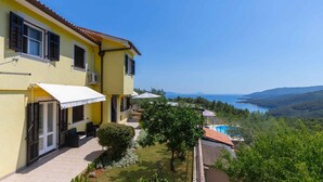 A yellow villa with a terrace, a swimming pool, and a view of the sea.