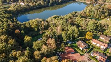 Vista aérea de una zona residencial con casas, un lago y vegetación circundante.