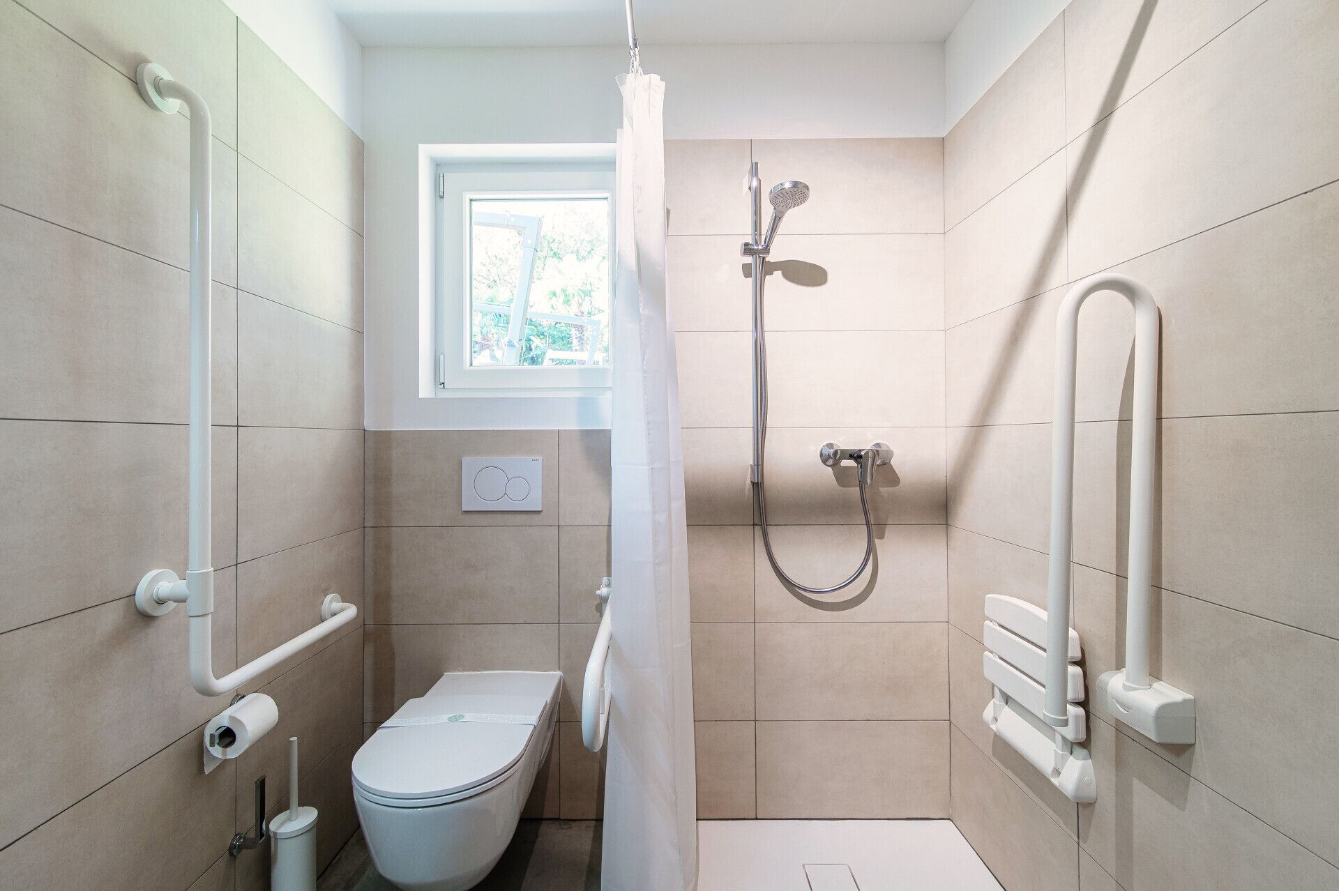 Une salle de bain moderne équipée d’une douche, de toilettes et de barres d’appui.