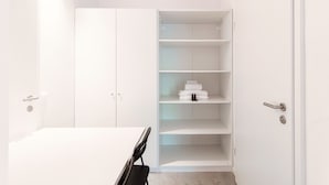A white room with a bed, a wardrobe, and a built-in shelving unit. - A barrier free studio apartment (LE BETULLE STUDIO 6) (Origlio)