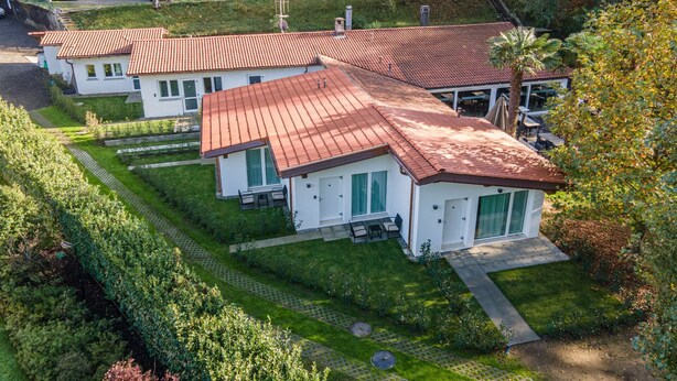Una filera de cases modernes amb teulades vermelles, disposades amb cura en una zona residencial amb jardins ben cuidats i una àrea de pàrquing visible al fons.