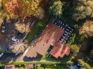 Vue aérienne d’une propriété comprenant un grand bâtiment, plusieurs places de stationnement et de nombreux espaces verts.